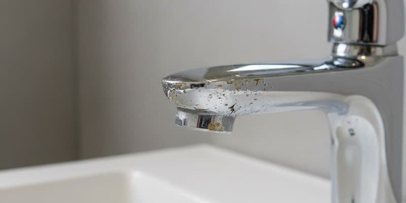 A close-up, cautionary photo of a faucet where the chrome finish is visibly flaking off, revealing the yellowish brass underneath.