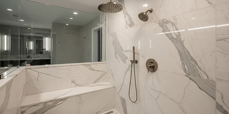 A stunning walk in shower with a large ceiling mounted rainfall showerhead. Water is falling gently